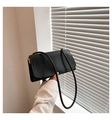 Detail view of a black minimalist leather shoulder bag with sleek gold metal hardware buckle - Black