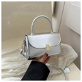 Détail d'un petit sac carré argenté métallisé avec boucle dorée et poignée haute - Argenté