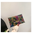 Detailansicht einer regenbogenfarbenen Umschlagtasche mit Wellenmuster und goldener Metallleiste - Schwarz