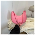 Pink croc-embossed crescent moon underarm bag held by hand in a modern interior - Pink