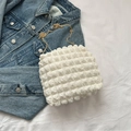 Weiße strukturierte Bubble-Tasche mit goldener Metallkette auf einer Jeansjacke - Weiß