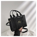 Détail du sac à main noir en cuir verni avec motif crocodile et lettrage doré - Noir