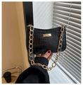 Gros plan d'un sac à main noir à texture croco avec chaîne dorée et plaque en métal - Noir