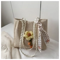 Detail der Strohtasche mit gelbem Blumenanhänger und einem gemusterten Seidentuch - Weiß