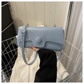 Detalle de bolso baguette azul claro con hebilla circular grande y herrajes plateados - Azul
