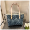 Detail van denimblauwe gewatteerde draagtas met crème bandjes en rode randen - Blauw