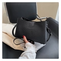 Detalle del bolso de mano negro con textura de cocodrilo, asa superior y cremallera metálica - Negro Puro