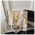 Detail of woven straw tote bag with yellow flower charm and decorative silk scarf - White