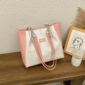 Sac fourre-tout bicolore rose et beige avec bandoulière posé sur un banc en bois sombre - Rose