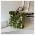 Detail of green woven tote bag featuring white grid patterns and fringed top edges - Green