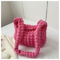Detalle de la textura plisada de burbujas rosa fucsia en un bolso de hombro moderno - rosa intenso