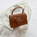 Borsa a mano quadrata marrone caramello con catena dorata su uno sfondo di blazer - Marrone