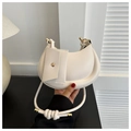 Primer plano de un bolso hobo crema con asa anudada y detalles en metal dorado - Blanco