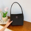 Minimalistische schwarze Nylon-Schultertasche mit rosa Stickerei auf Holzoberfläche - Schwarz