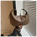 Primer plano del cuero PU marrón con textura lichi en un bolso hobo de media luna minimalista - café