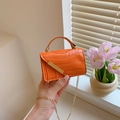 Mini bolso naranja con textura de cocodrilo y cadena dorada sobre el alféizar - Naranja