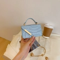 Light blue stone pattern mini bag with gold chain strap and top handle in lifestyle setting - Blue