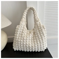 Dettaglio del tessuto beige con trama popcorn e design a pieghe su una borsa tote - Bianco