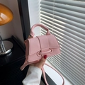 Pink mini hourglass leather handbag with a top handle and shoulder strap in an indoor setting - Pink