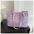 Close-up of purple popcorn textured tote bag featuring a pink fashion label and slim straps - Purple