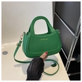 Detail of green crescent handbag with gold hardware and adjustable strap on white background - Green