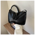 Close-up of minimalist black leather tote bag featuring sleek dual metal zippers and strap - Black