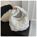 Detail of glossy quilted puffer bag with iridescent finish and knotted handle design - White