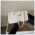 Détail d'un sac à main blanc à motif crocodile avec fermoir doré sur un bureau en bois - Blanc