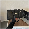 Détail du sac noir en cuir motif crocodile avec fermoir doré sur un bureau en bois - Noir