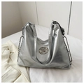 Close-up of shiny silver metallic tote bag featuring double handles and chain decorations - Silver