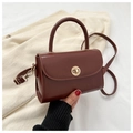 Detail of vintage brown leather handbag featuring a golden circular twist lock and handle - Dark Brown