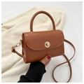 Detail of vintage brown leather handbag with gold metal twist lock on knit background - Tan