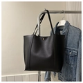 Close-up of black leather tote bag featuring a gold button clasp and matte texture - Black