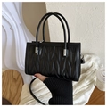 Detalle de bolso acolchado negro con costuras onduladas verticales y herrajes plata - Negro
