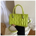 Detalle macro de bolso verde lima con pliegues en V en 3D y herrajes plateados elegantes - Verde