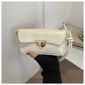 Detailed close-up of cream minimalist flap bag with vintage golden triangular buckle - White