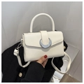 Details einer weißen Lederhandtasche mit silberner Mond-Schnalle und Trageriemen - Weiß