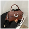 Detail einer braunen Leder-Handtasche mit einer silbernen Metall-Schnalle in Halbmondform - Dunkelbraun