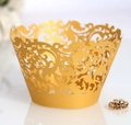 Macro shot of gold laser-cut hollow filigree cupcake wrappers for elegant party desserts - Gold