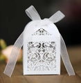 Macro shot of white laser-cut house-shaped favor box with floral patterns and organza ribbon - White