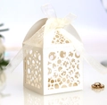 Close-up of cream white laser-cut favor box with intricate patterns and satin ribbon - Ivory
