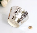 Detailed macro view of laser-cut silver cupcake wrappers with vintage baroque patterns - Reflective Silver