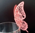Close-up of pink laser-cut butterfly place card on glass rim for wedding decor - Pink