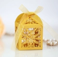 Detail of laser-cut snowflake patterns on a golden gift box with a sheer ribbon bow - Gold