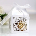 Close-up of white laser-cut wedding favor box with heart patterns and white ribbon bow - White