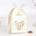 Macro detail of laser-cut hollow heart candy box with LOVE text and white silk ribbon - Ivory