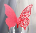 Close-up of laser-cut butterfly place card with magenta glitter on a glass rim - Red