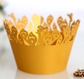 Detailed macro view of golden laser-cut cupcake wrappers with lace peacock feather patterns - Gold