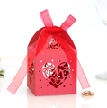 Close-up of laser-cut red paper wedding favor box with LOVE text and ribbon bow - Pearlescent Red