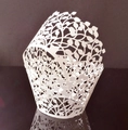 Macro shot of laser-cut leaf pattern on white cupcake wrappers for wedding dessert decor - White